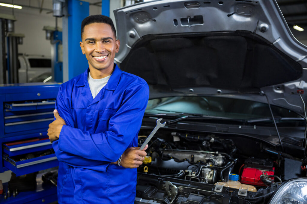 Portrait of smiling mechanic with arms crossed and spanner at the repair garage